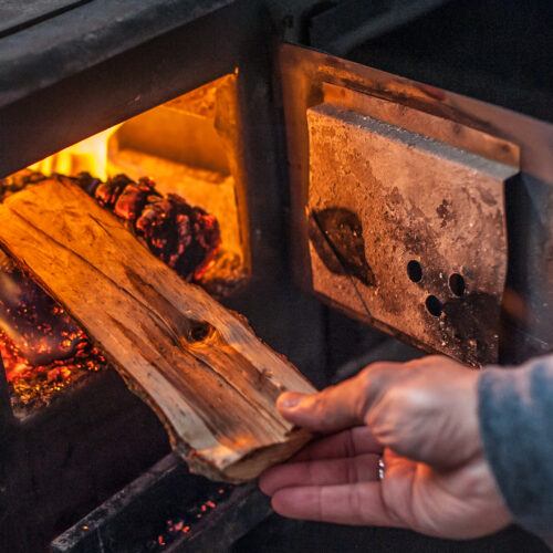 Man putting log to wood burning stove. Close up