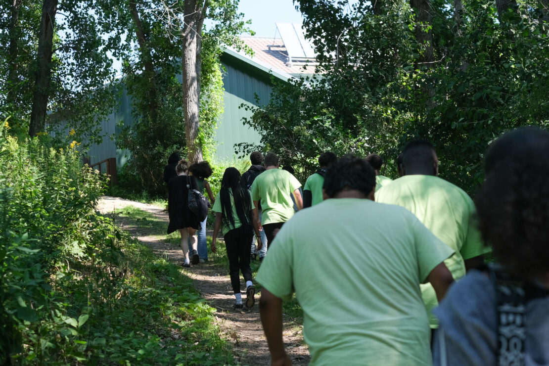 A group of youth in green shirts walking a nature trail.