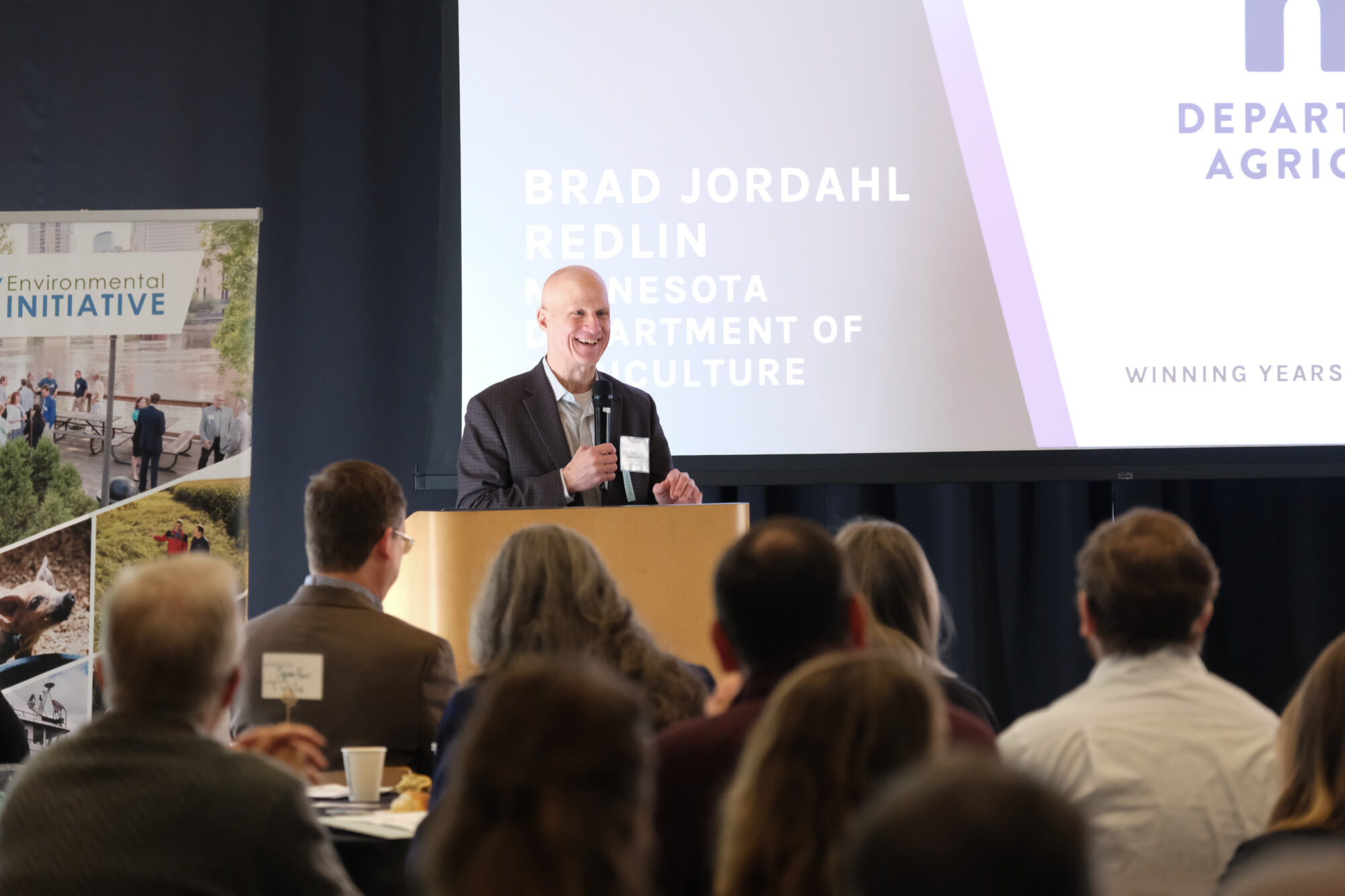 Speaker Brad Jordahl Redlin of the Minnesota Department of Agriculture smiles at the podium.