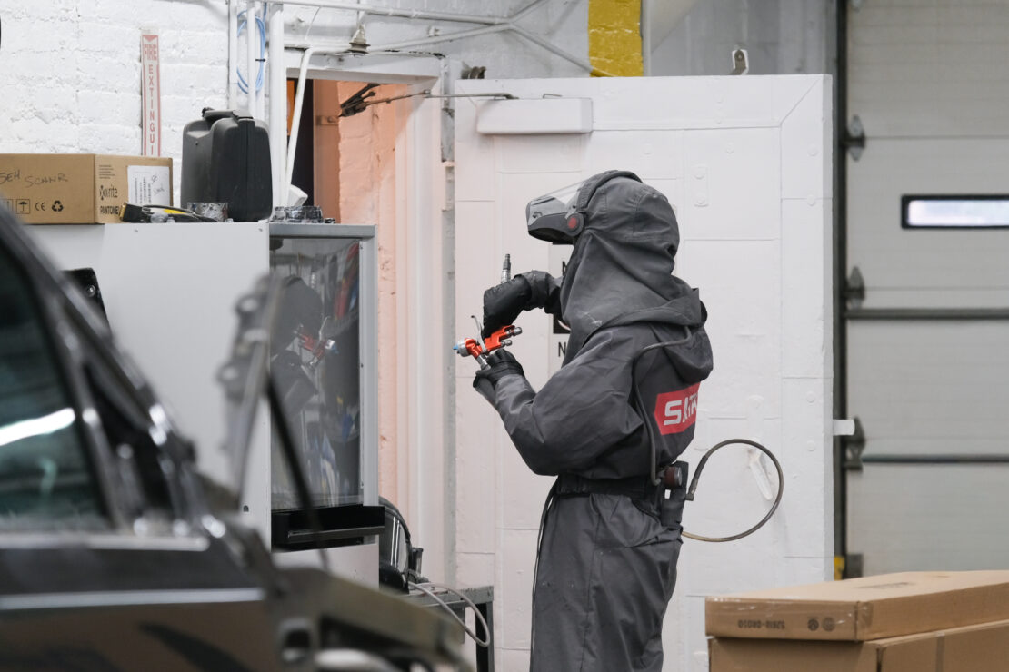 Employee at Hagen’s Auto Body prepares a paint gun for spraying inside the booth.