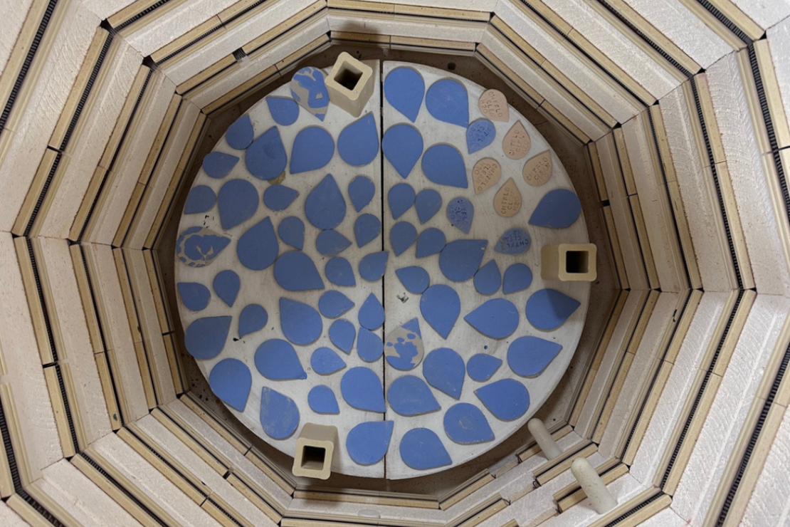 Blue ceramic tiles in the shape of water droplets waiting to be fired in a kiln.
