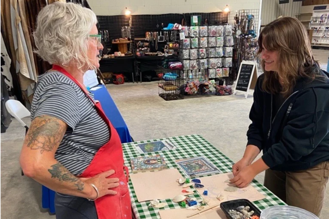Artist Mary Beth Magyar talks to a fairgoer at the Fillmore County Fair.